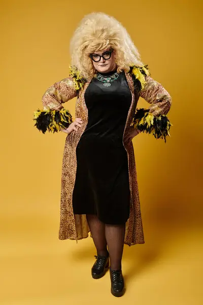A glamorous queer person stands confidently in a leopard-print robe, adorned with black feathers. — Stock Photo