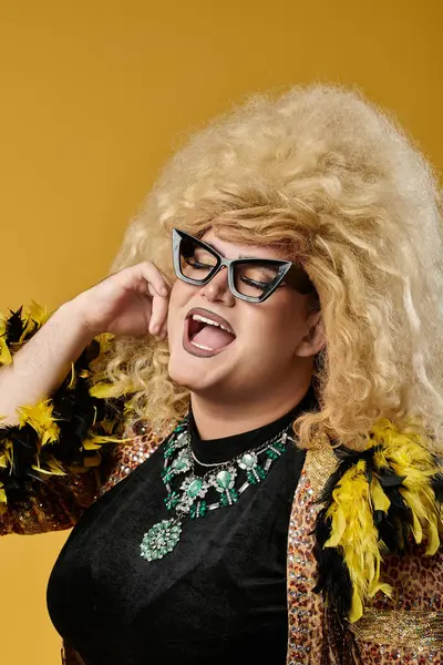 A queer person in a glamorous outfit laughs brightly while wearing a large wig and stylish glasses. — Stock Photo