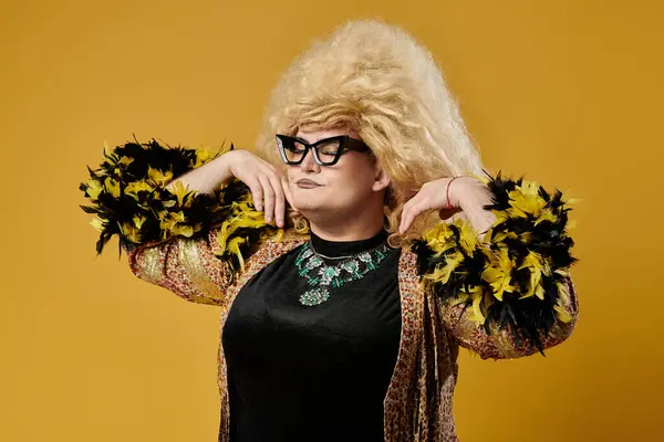 Una persona queer con una chaqueta emplumada posa con una expresión dramática. - foto de stock