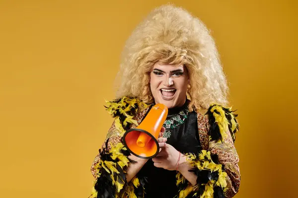 A queer person in a large blonde wig and fashionable attire holds a megaphone. — Stock Photo