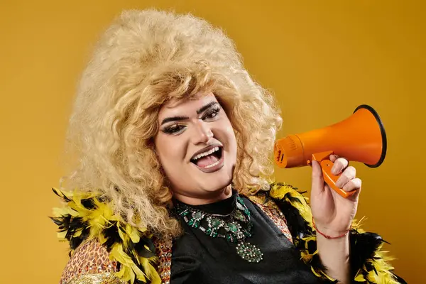 A drag queen with a large blonde wig smiles while holding a megaphone. — Stock Photo