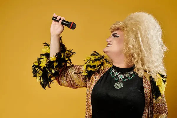 A drag queen dressed in stylish clothing with feathers performs with a microphone. — Stock Photo