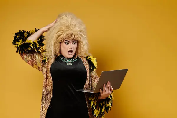 Uma drag queen em uma roupa elegante olha de surpresa para um laptop. — Fotografia de Stock