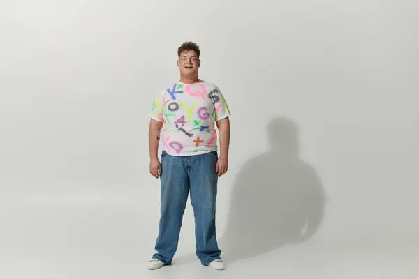 A queer person smiles brightly in a white shirt with colorful letters. — Stock Photo
