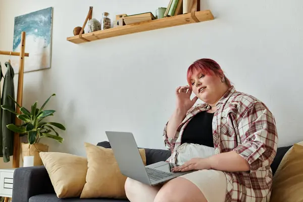 A woman relaxes on a couch in her living room, using a laptop. — Stock Photo