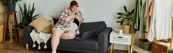 A woman sits on a couch in her home, smiling and relaxed. — Stock Photo