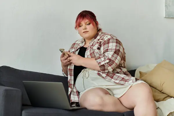 A woman relaxes on her couch, checking her phone. — Stock Photo