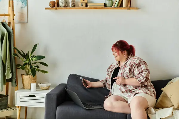 A woman relaxes on a couch in her home, smiling as she uses her phone. — Stock Photo