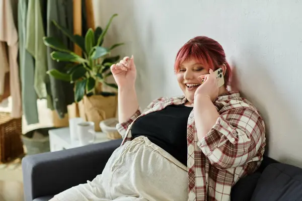 A woman with pink hair laughs while talking on the phone. — Stock Photo