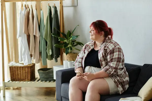 Красивая женщина plus size отдыхает дома на диване, держа в руках телефон. — стоковое фото