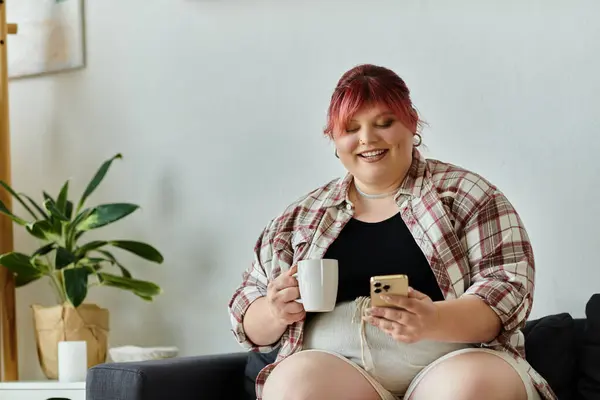 A plus size woman enjoys a cup of coffee while scrolling through her phone. — Stock Photo