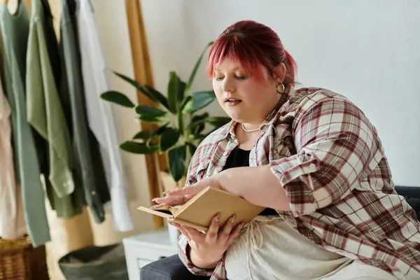 A woman sits comfortably at home, lost in a book. — Stock Photo
