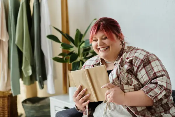 A woman smiles as she reads a book at home. — Stock Photo