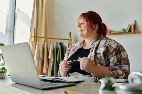 A plus-size woman smiles while working at her home office desk. — Stock Photo