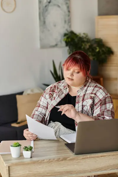 Une femme en chemise à carreaux travaille à la maison, entourée de plantes. — Photo de stock
