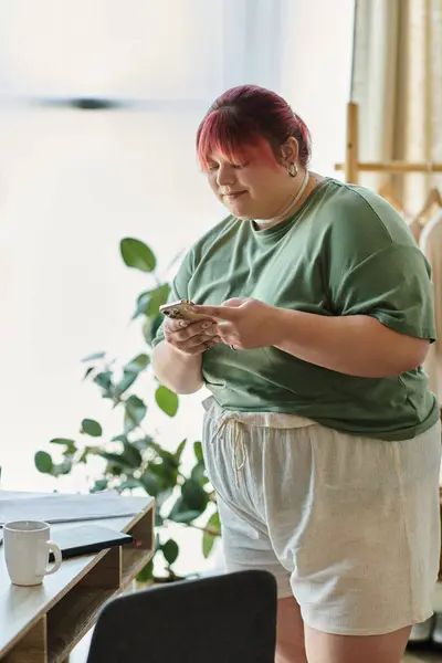A woman with pink hair sits at home, casually browsing her phone. — Stock Photo