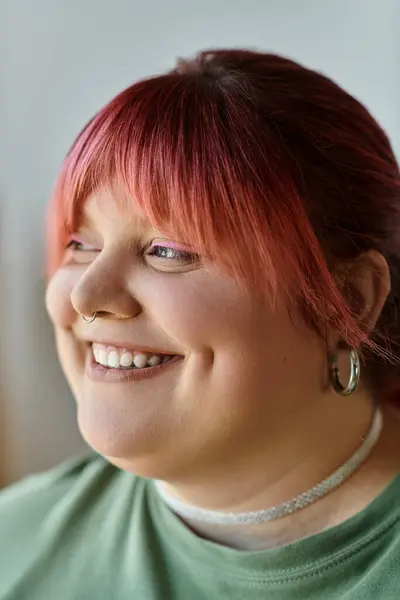 Женщина plus-size с розовыми волосами ярко улыбается, проводя время дома. — стоковое фото