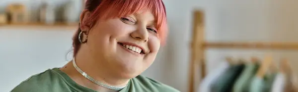 A woman with pink hair smiles brightly in her home. — Stock Photo