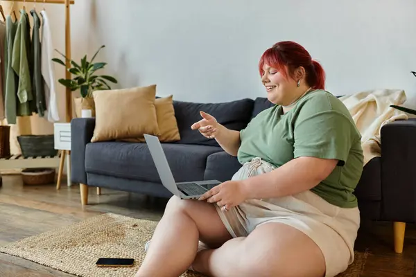 Una donna plus-size sul pavimento sorridente e videochiamata — Stock Photo