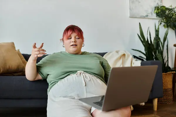 Eine Frau entspannt sich auf einer Couch und führt einen Videoanruf auf ihrem Laptop durch. — Stockfoto