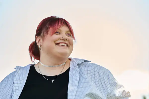 A woman with pink hair looks up and smiles against a bright, hazy sky. — Stock Photo