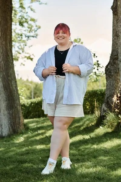 Uma mulher plus-size está em um parque gramado, sorrindo brilhantemente. — Fotografia de Stock