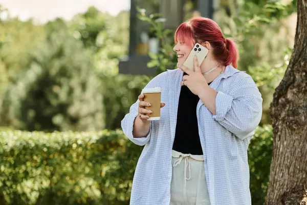 A woman with pink hair talks on her phone while enjoying a cup of coffee. — Stock Photo