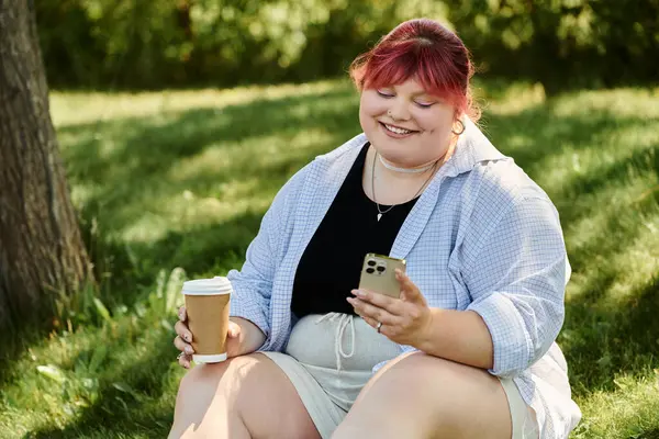 Woman with pink hair smiles, enjoys coffee in park, scrolls phone — Stock Photo