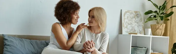 Two women in cozy homewear share a tender moment on their bed, their eyes locked in a loving gaze. — Stock Photo