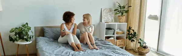 Due donne in biancheria intima accogliente rilassarsi su un letto, condividendo un momento di tranquillità insieme. — Foto stock