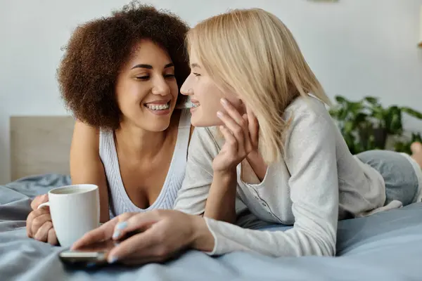 A lesbian couple enjoys a relaxed morning, sharing a cozy moment on their bed, lost in conversation. — Stock Photo