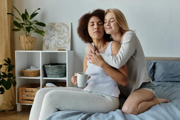 A loving lesbian couple cuddles on the bed, enjoying a moment of intimacy and comfort in their home. — Stock Photo