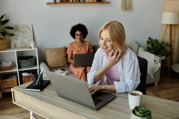 Una coppia lavora da casa, una su un computer portatile e l'altra su una telefonata.. — Foto stock