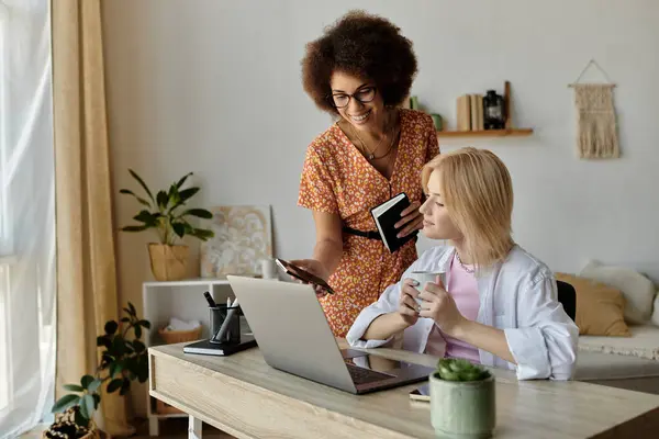 Two women, one with glasses, the other blonde, work together in a home office. — Stock Photo
