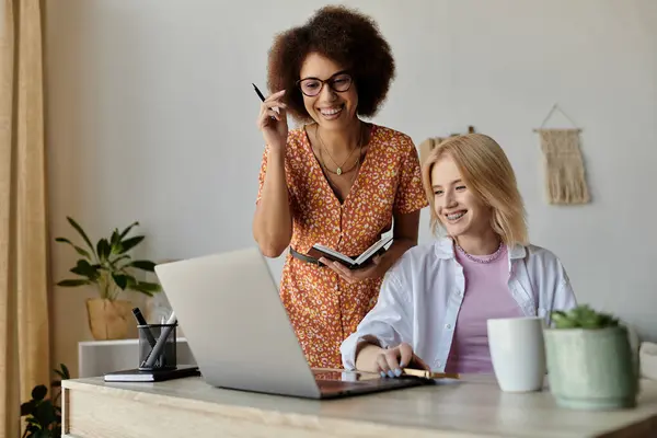 Two women work from home, one using a laptop and the other holding a notebook. — Stock Photo