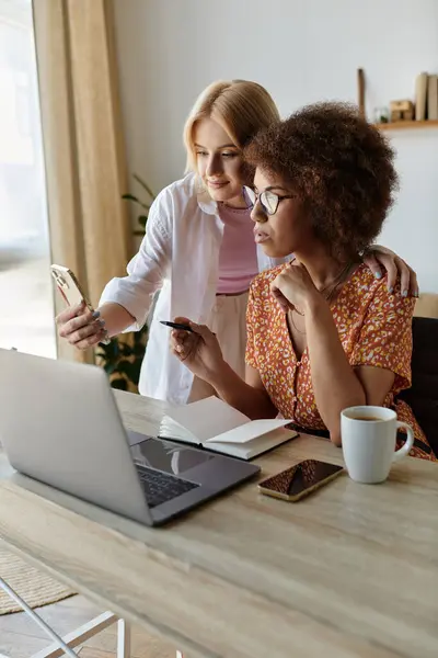 Two women work together on a project at home, using a laptop and smartphone. — Stock Photo
