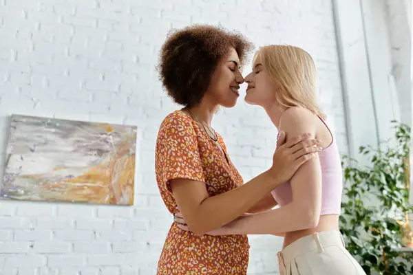 A multicultural lesbian couple embraces in their modern apartment. — Stock Photo