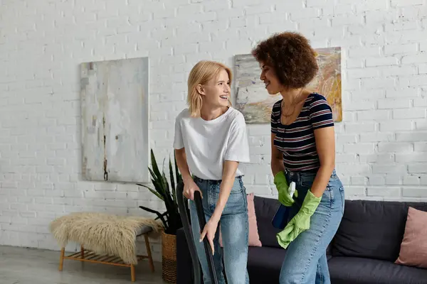 Um casal lésbico desfruta de um momento de riso compartilhado enquanto limpa seu apartamento moderno. — Fotografia de Stock