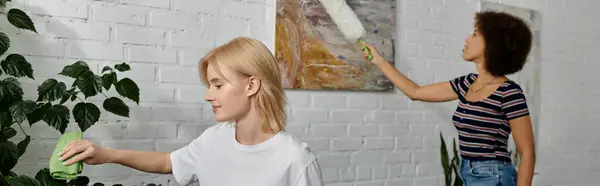 Duas mulheres, uma com cabelo loiro e outra com cabelo castanho encaracolado, limpam o apartamento moderno juntas.. — Fotografia de Stock