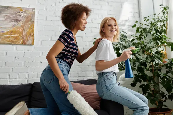 Um casal lésbico limpa seu apartamento juntos, desfrutando de um momento de riso e união. — Fotografia de Stock