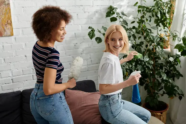 Ein lesbisches Paar putzt seine moderne Wohnung, ihr Lachen und ihre Freude erfüllen die Luft. — Stockfoto