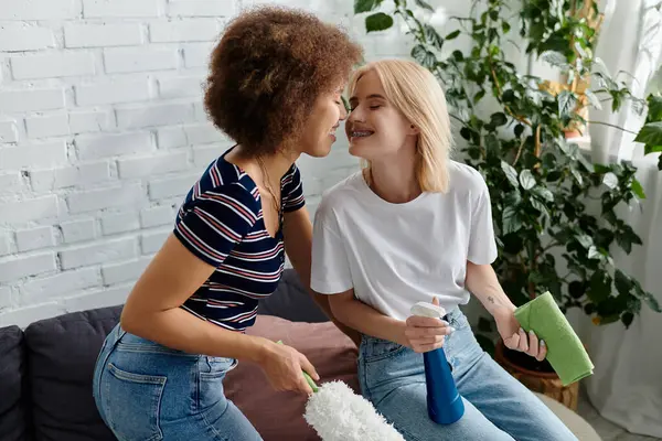Um casal lésbico multicultural limpa seu apartamento moderno juntos, compartilhando um momento de intimidade enquanto trabalha em suas tarefas.. — Fotografia de Stock