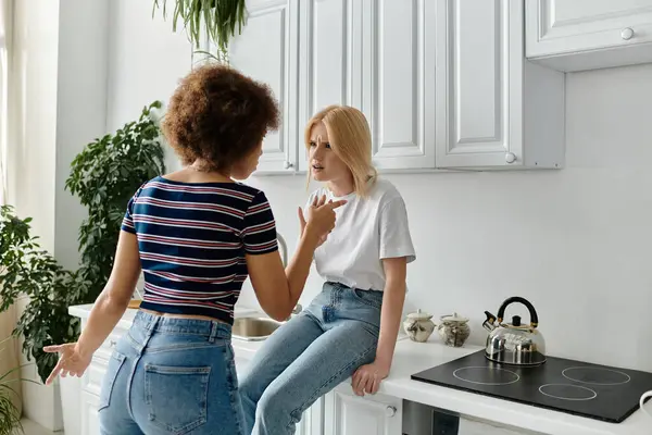 Deux femmes, un couple de lesbiennes, se disputent dans une cuisine. Ils ont tous deux l'air mécontents.. — Photo de stock