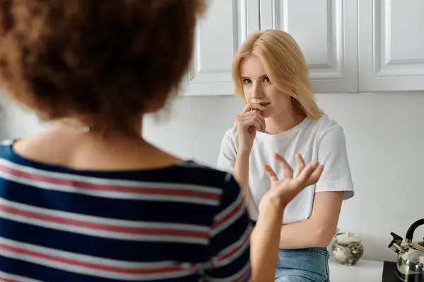 Deux femmes dans une cuisine semblent se disputer. L'un a l'air mécontent de l'autre qui lui mord la lèvre et regarde ailleurs — Photo de stock