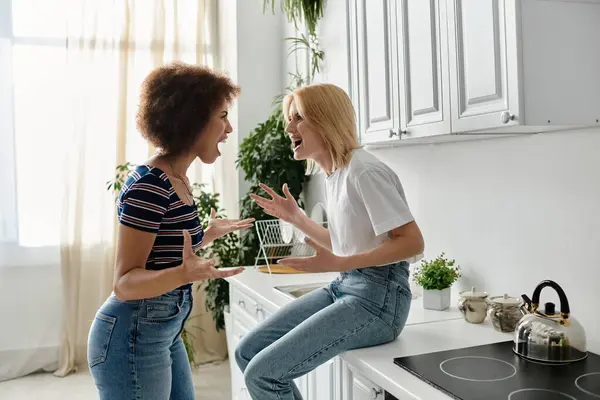 Two women argue heatedly in a modern kitchen, their relationship strained. — Stock Photo