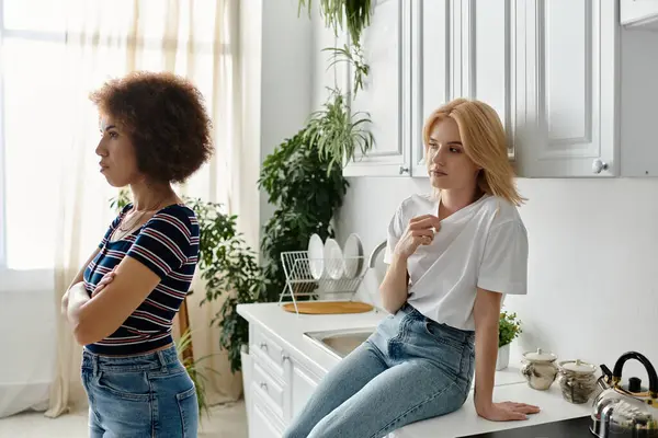 Zwei Frauen, scheinbar ein Paar, stehen in ihrer Küche und liefern sich einen hitzigen Streit, in dem sie ihrem Unmut und Missverständnis Ausdruck verleihen.. — Stockfoto