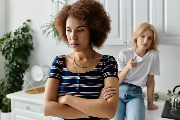 Dos mujeres están discutiendo en una cocina, una con los brazos cruzados y una expresión disgustada, la otra señalando un dedo hacia ella. — Stock Photo