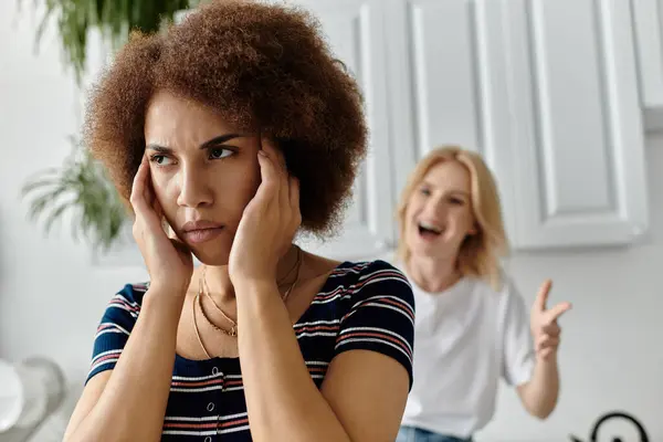 Un couple lesbien multiculturel se dispute dans la cuisine, avec une femme en détresse tandis que l'autre fait un geste énergique. — Photo de stock