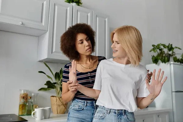 Una pareja lesbiana discute en la cocina, sus expresiones muestran tensión y disgusto. - foto de stock