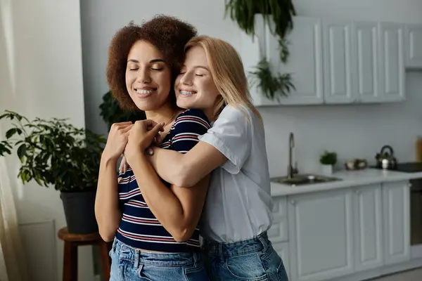 A lesbian couple embraces in the kitchen, their smiles showing signs of connection. — Stock Photo